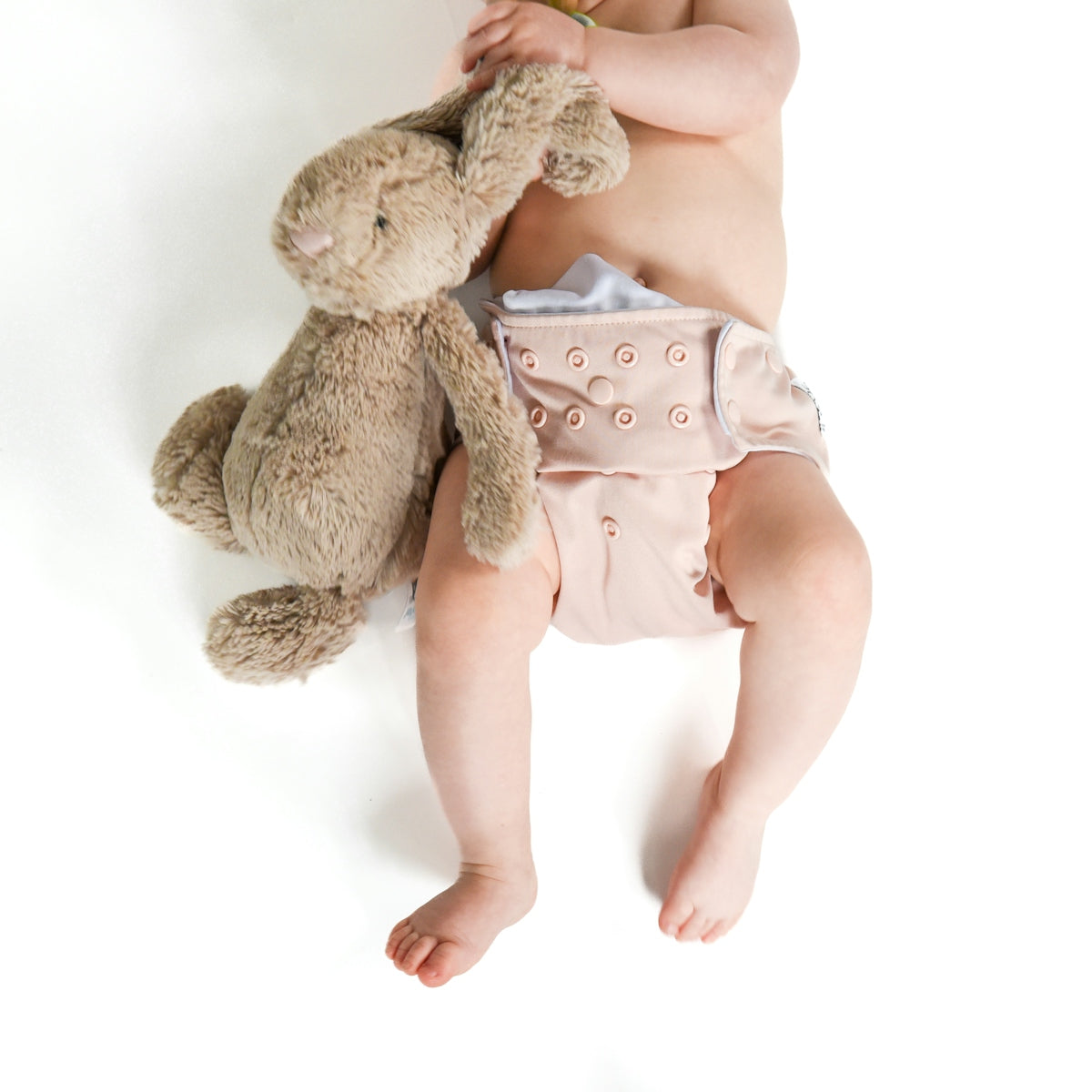 a baby in a diaper holding a teddy bear