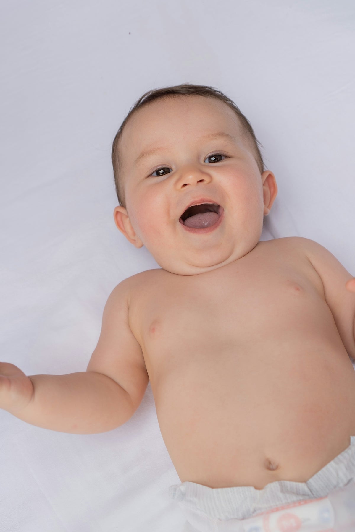 A baby is laying on a white sheet