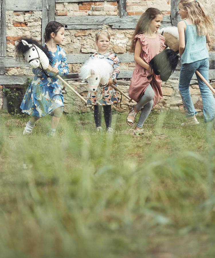 Fröhliche Kinder reiten ihr Hobby-Horse