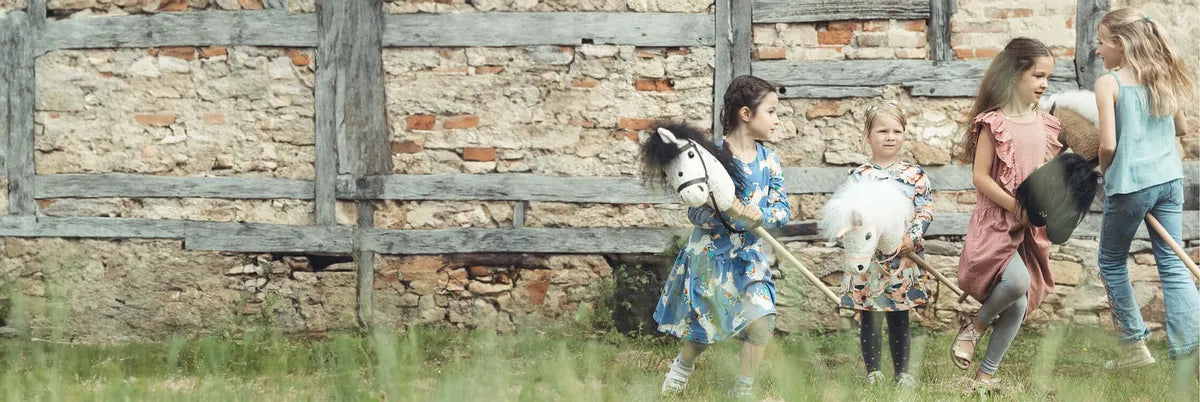 Kinder reiten auf handgemachten Bio-Steckenpferden von PAT & PATTY – nachhaltiges Spielzeug aus Stoff.