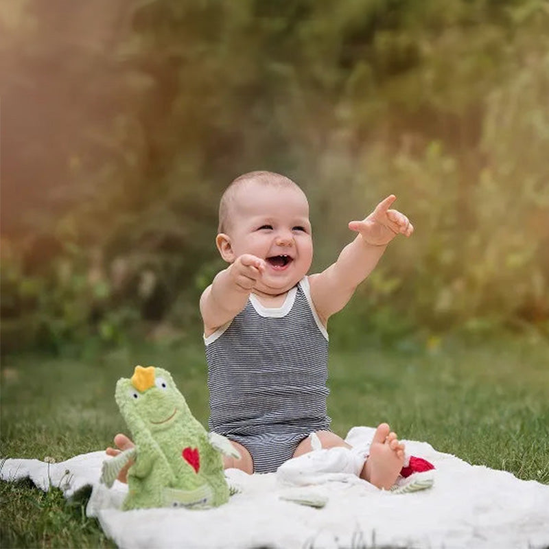 Kleines Kind sitzt auf einer Decke mit Kissen und spielt mit Bio-Spielzeugen von PAT&PATTY