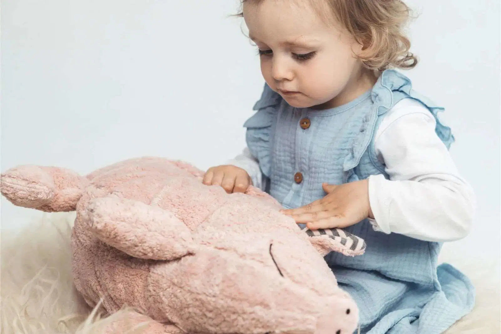 Mädchen spielt mit ein rosa Schwein Kuschelkissen
