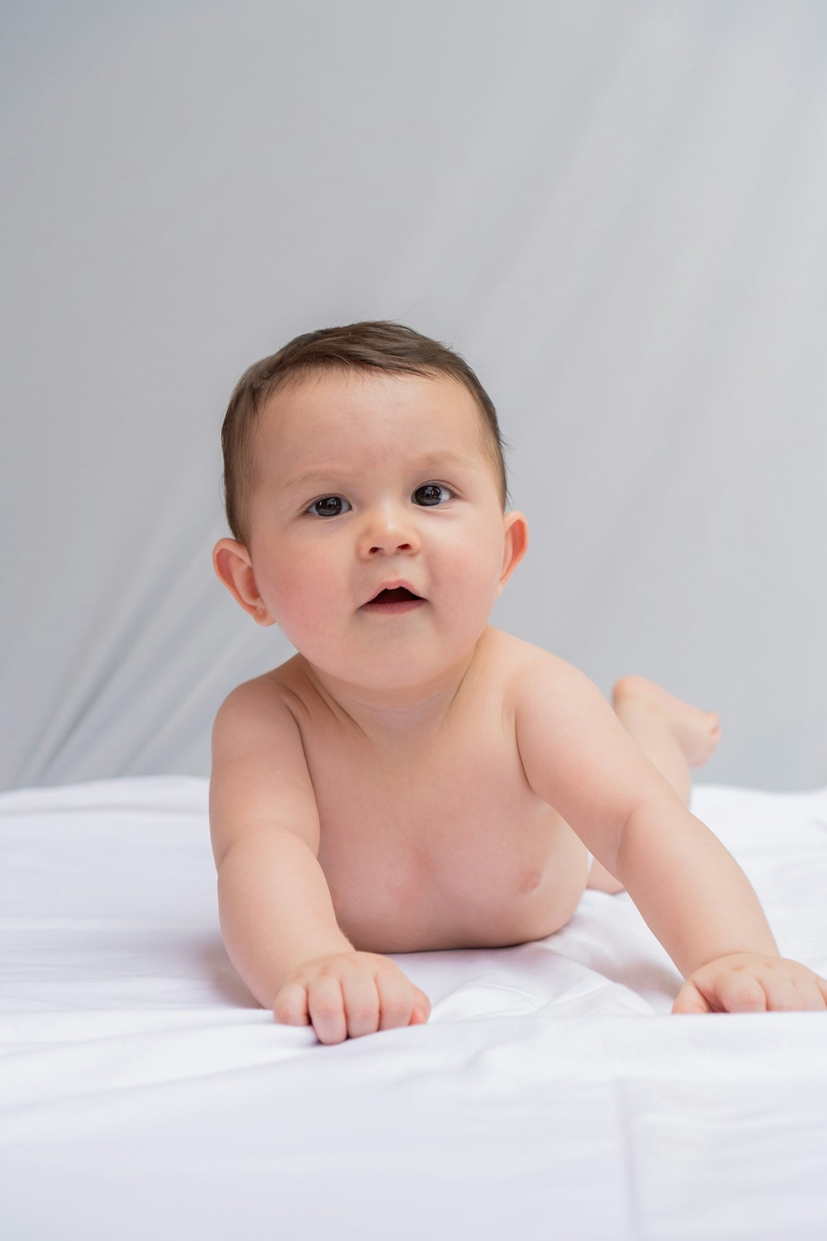 A baby is laying on a white sheet