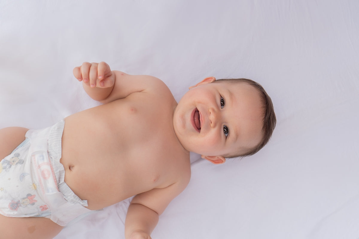 A baby in a diaper laying on a white sheet
