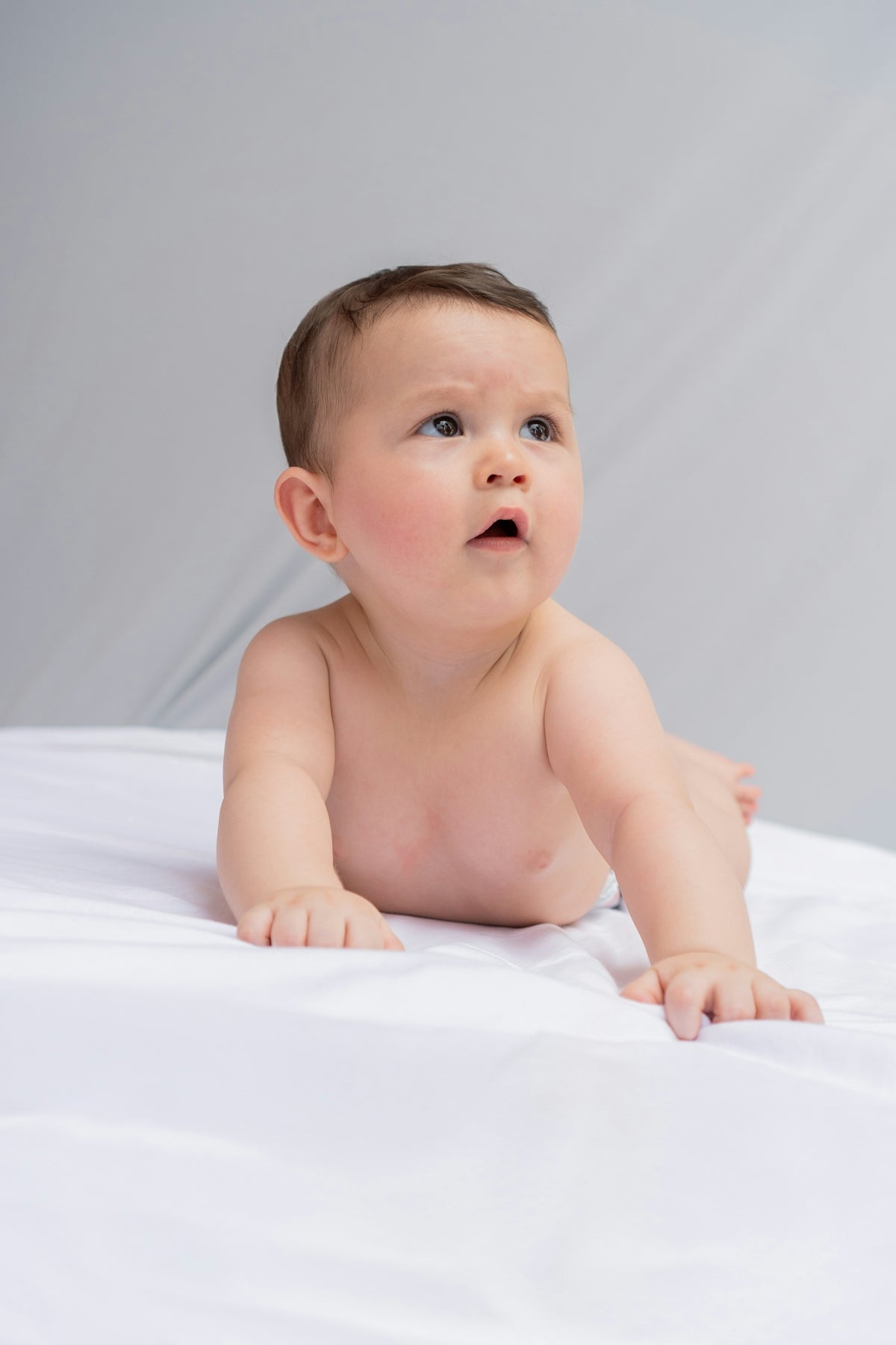 A baby is laying on a white sheet